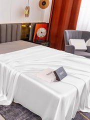 White 19 Momme Mulberry Silk seamless flat sheet draped on a bed, with two product boxes.