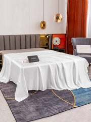 White 19 Momme Mulberry Silk seamless flat sheet draped over a bed, with a black gift box.