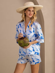 Women's Ice Leaf print mulberry silk short sleeve button-up pajama set with straw hat, holding a coconut.