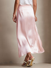 Women's pink 19 Momme mulberry silk A-line maxi skirt with a zipper design, worn with white heels.