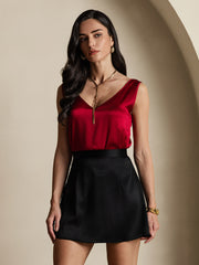 Woman in a red mulberry silk v-neck top and black silk A-line mini skirt with zipper design.