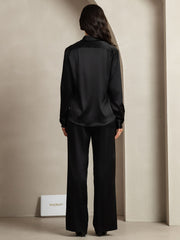 Women's black 19 Momme mulberry silk button-up shirt and wide-leg pants set, seen from behind.
