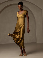 Woman in a flowing gold 19 Momme mulberry silk cap sleeve round neck midi dress.