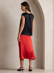 Women's black 19 Momme mulberry silk cap sleeve round neck top, paired with a red skirt.