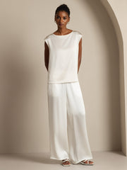 Woman in a white 19 Momme mulberry silk cap sleeve round neck top and matching wide-leg pants.