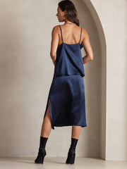 Woman in navy blue mulberry silk cowl neck camisole top and matching skirt with side slit.