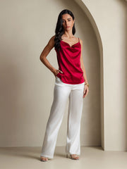 Woman in a red 19 Momme mulberry silk cowl neck camisole top and white silk pants.