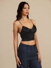 Woman wearing a black 19 Momme mulberry silk crop top camisole with spaghetti straps and a V-neck.