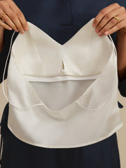 Woman holding a white mulberry silk crop top camisole with spaghetti straps and a built-in bra.