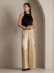 Woman wearing fashionable black silk top and flowy high-slit mulberry silk palazzo pants.
