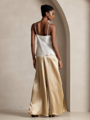 Woman in white mulberry silk top and gold flowy high-slit palazzo pants.