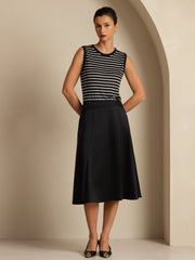 Woman in a black and white striped top and a black high-waist A-line midi skirt.