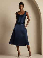Woman wearing a navy 19Momme mulberry silk high-waist A-line midi skirt with pockets and matching silk top.