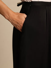 Black 19Momme mulberry silk high-waist A-line pleated midi skirt with a hand in the pocket.
