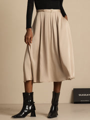 Beige 19Momme mulberry silk high-waist A-line pleated midi skirt with pockets, worn with black top and boots.