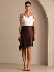 Women's mulberry silk high-waist asymmetrical brown skirt with black lace hem, paired with a white silk camisole.