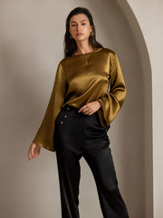 Woman in olive green silk top and black high-waist straight-fit pants with side buttons.