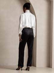 Woman in black 19Momme silk high waist straight fit pants with zipper side pockets and a white silk blouse.