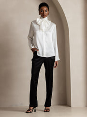Woman in white 19 Momme silk high-waist straight-fit pants with zipper side pockets, paired with a white silk blouse.