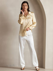 Women's 19Momme mulberry silk high waist wide leg pleated pants in white, paired with a gold silk top.