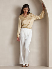 Women's gold mulberry silk long-sleeve shirt and white high-waist wide-leg pleated pants.