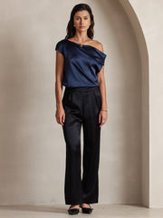 Woman in black 19Momme silk high waist wide leg pleated pants and a navy off-the-shoulder silk top.
