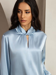 Light blue 19Momme mulberry silk keyhole neck blouse with a subtle sheen, worn by a woman.