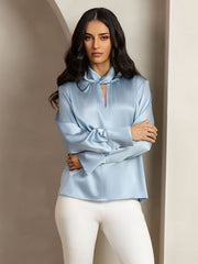 Light blue 19 Momme mulberry silk keyhole neck blouse with pearl buttons, worn by a woman.