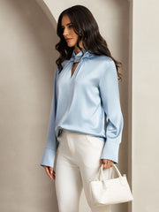 Light blue mulberry silk keyhole neck blouse with pearl buttons, worn by a woman.