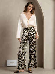 Women's 19Momme mulberry silk leopard print straight leg pants with side pockets, paired with a cream silk top.