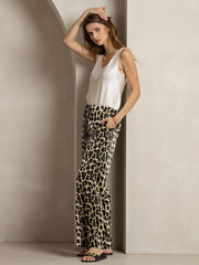 Woman in 19Momme mulberry silk leopard print wide leg pants with side pockets and a white silk top.