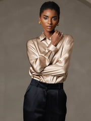 Women's gold mulberry silk long sleeve lapel collar shirt with black trousers.