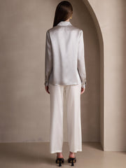 Women's silver 19 Momme mulberry silk long-sleeve lapel collar shirt with white pants.