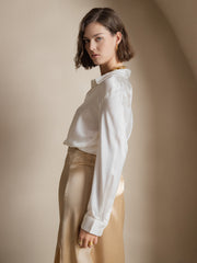 Women's white 19Momme mulberry silk long-sleeve lapel collar button-up shirt paired with a gold skirt.