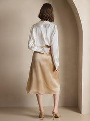 Woman in a white 19 Momme mulberry silk long-sleeve lapel collar shirt and a champagne silk midi skirt.