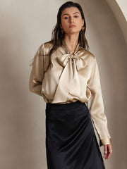 Women's champagne mulberry silk long sleeve tie neck blouse with a black skirt.