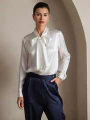 White 19Momme mulberry silk long sleeve tie neck blouse with a bow, paired with navy silk pants.