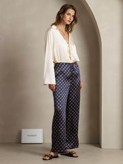 Women's navy chain print wide-leg mulberry silk pants with side pockets, paired with a cream silk blouse.