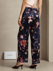 Women's navy mulberry silk wide-leg pants with a vibrant floral and bird print, featuring side pockets.