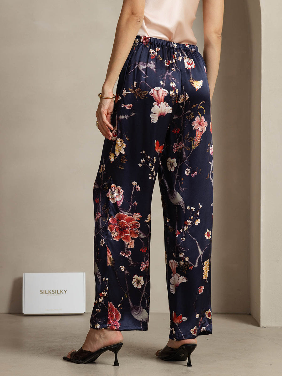 Women's navy mulberry silk wide-leg pants with a vibrant floral and bird print, featuring side pockets.