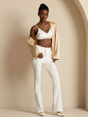 Woman in a relaxed long-sleeve tie-front mulberry silk cardigan, white bralette, and white pants.