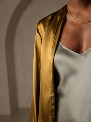 Women's gold 19Momme mulberry silk relaxed long sleeve tie-front cardigan over a grey silk top.