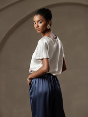Woman in a white 19 Momme mulberry silk short sleeve boat neck t-shirt and navy silk pants.