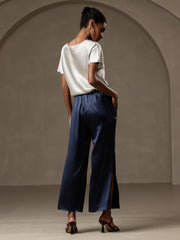 Woman in a white 19 Momme silk short sleeve boat neck T-shirt and navy wide-leg silk pants.