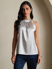 Women's sleeveless mulberry silk halter neck top in light grey, paired with navy pants.