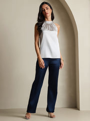 Women's sleeveless mulberry silk halter neck top in silver, paired with navy wide-leg pants.