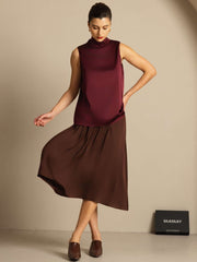 Women's mulberry silk sleeveless tie-neck blouse in burgundy, paired with a brown skirt.