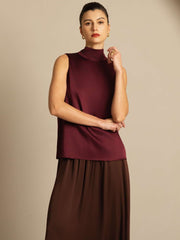 Women's mulberry silk sleeveless tie-neck blouse in burgundy, paired with a brown skirt.