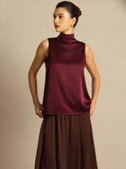 Women's mulberry silk sleeveless tie-neck blouse in rich burgundy, paired with a brown skirt.