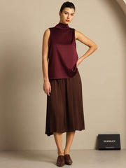 Women's mulberry silk sleeveless tie-neck blouse in burgundy, paired with a brown midi skirt.
